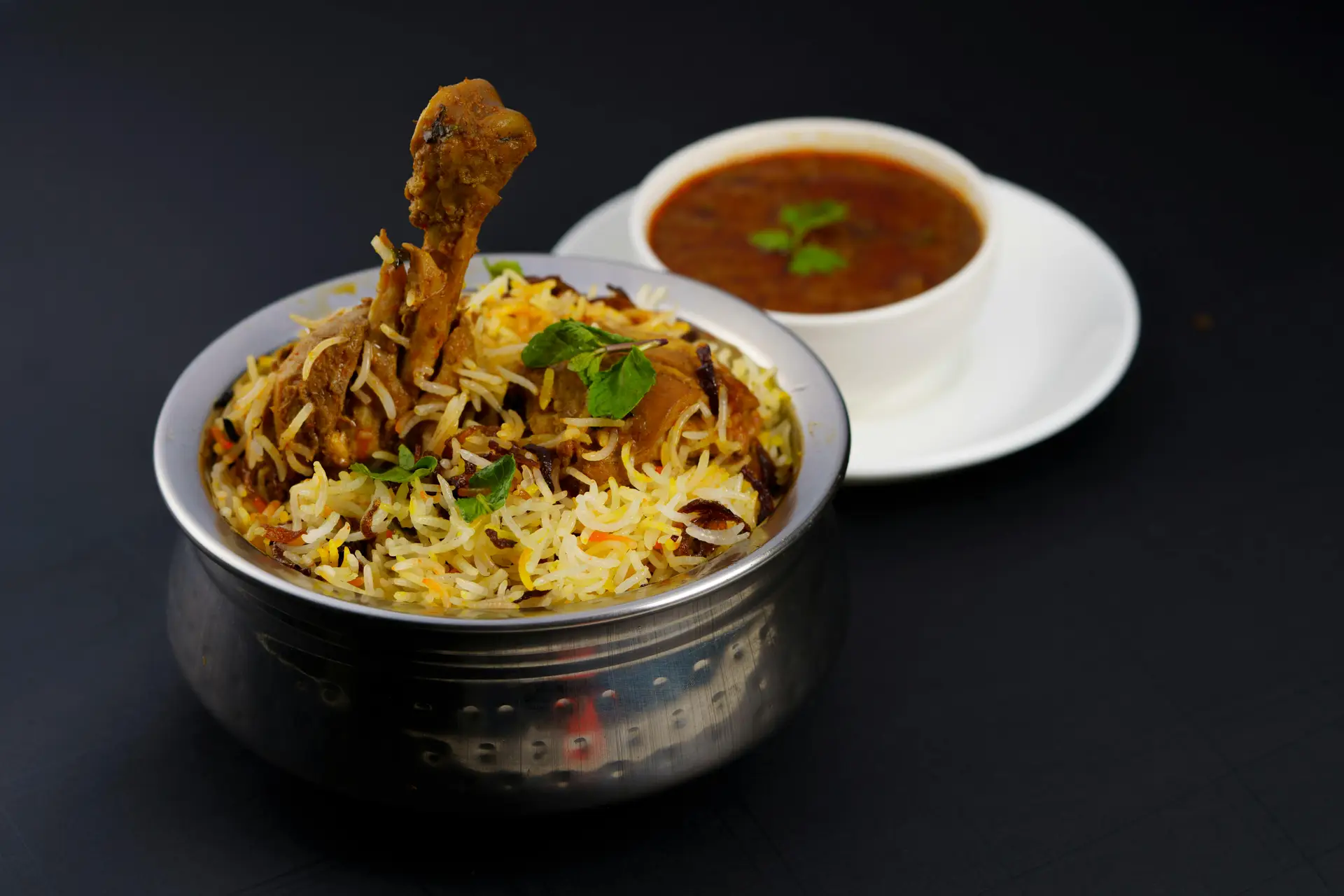 Flavorful chicken biryani served with spicy curry, a traditional Indian dish.