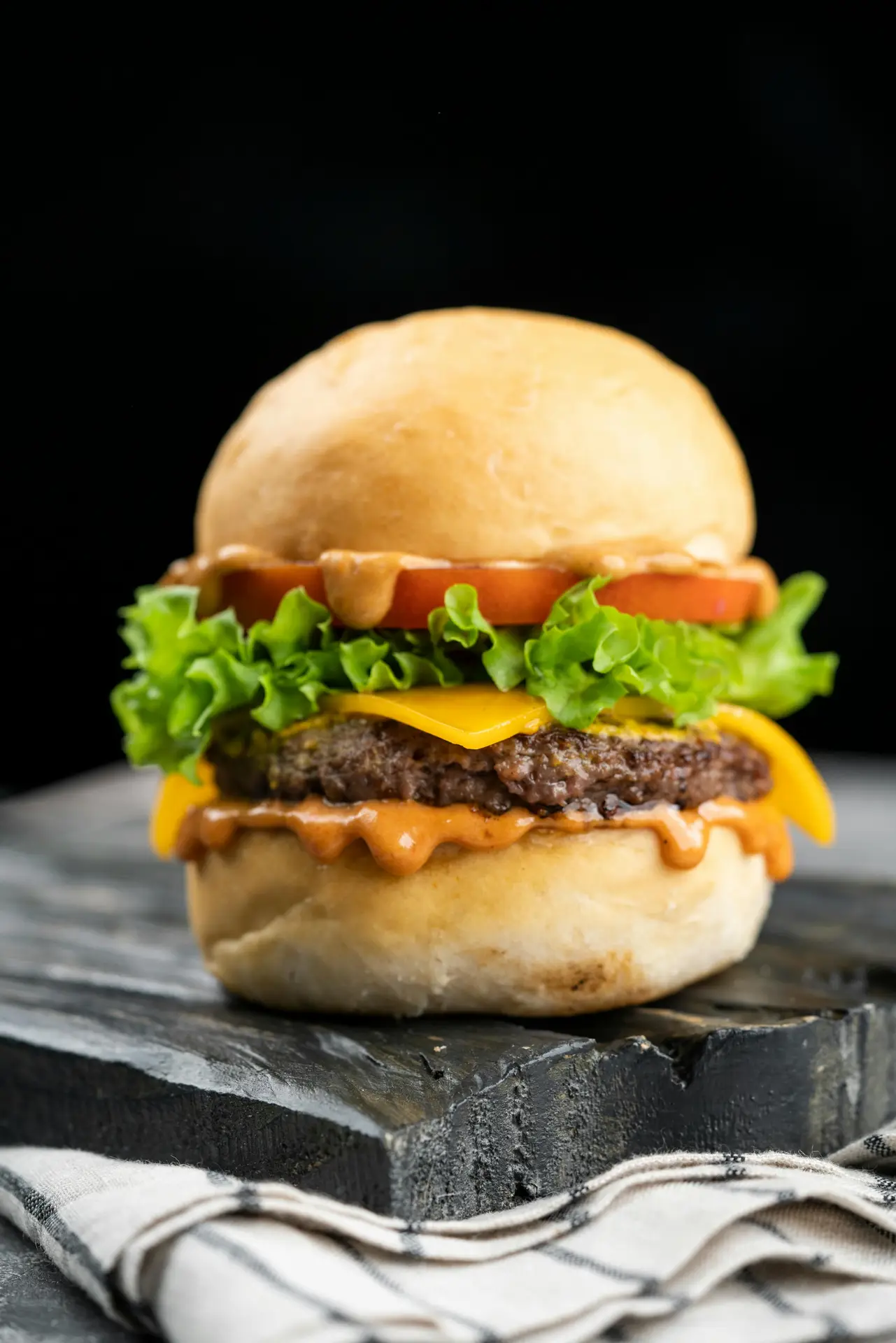 Mouthwatering close-up of a juicy cheeseburger with fresh lettuce and tomato.